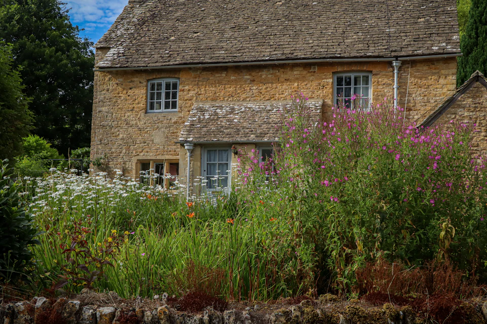 Casa de piedra con flores delante de la fachada
